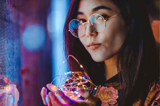 a woman holding a string of lights