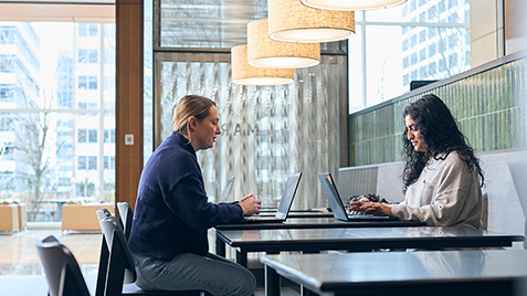a person and person sitting at a table with laptops