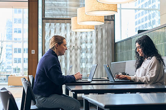 a person and person sitting at a table with laptops