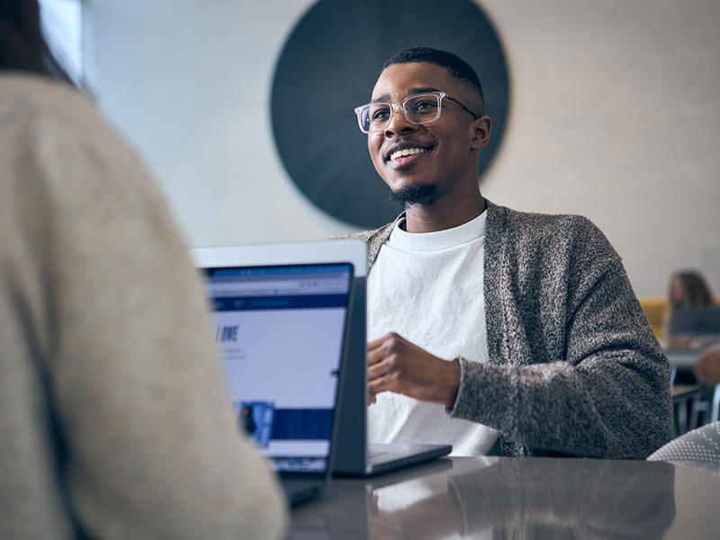 a person sitting at a table with a laptop
