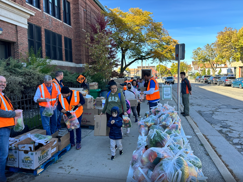 a group of people standing on a sidewalk with bags of food